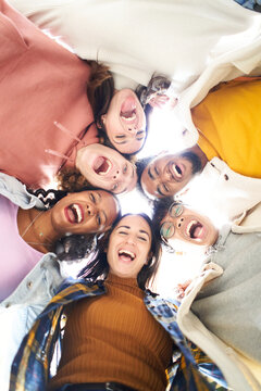 Vertical photo of a Circle of six happy people looking at the camera embracing and having a fun.