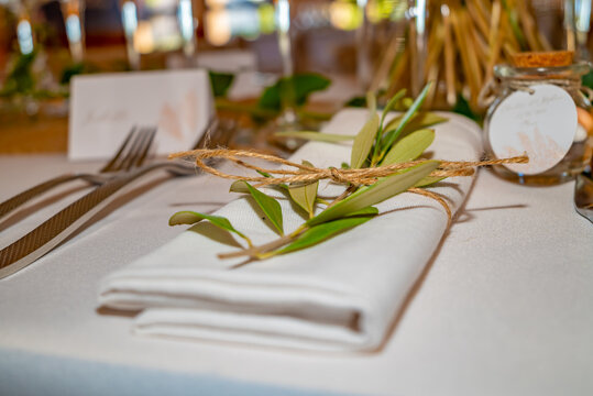 Mise en place sur une table avec un rameau d'olivier sur une serviette et une petite  ficelle de coton lors d'un mariage