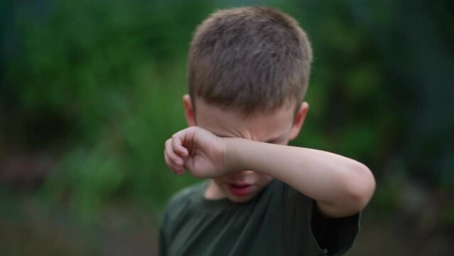 Upset boy wiping tears with his hand. Childish resentment