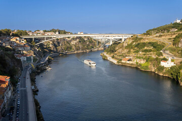 A view of the Douro River with a sailing cruise ship and the bridges in Porto