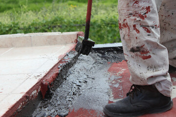 Construction worker applying 
black waterproofing material on roof