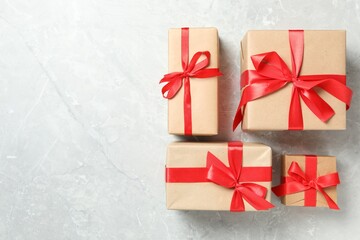Christmas gift boxes with red bows on light grey marble background, flat lay. Space for text