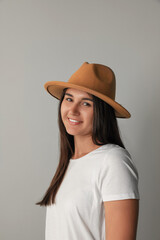 Smiling young woman in stylish outfit on light grey background