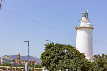 Malaga lighthouse in the foreground and the cathedral in the background with mountains in the distance