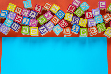 Wooden multicolored blocks with letters on orange background. Education for preschooler, reading, alphabet. Back to school concept