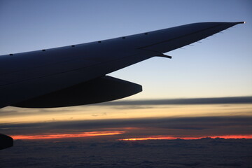 雲海に沈む夕陽に染まる飛行機