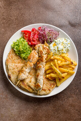 souvlaki with chicken and pita on white plate, Greek cuisine top view on brown table