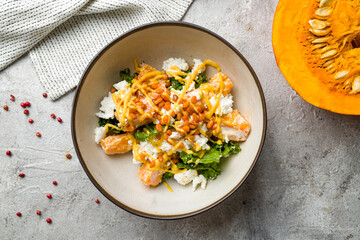 salad with pumpkin, cheese and herbs on plate on grey table top view