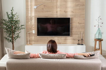 Girl in a relaxed pose on the sofa in the living room in front of the TV