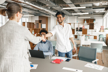 Smiling female boss leader shaking hand of new team member recruiting him for job on staff briefin