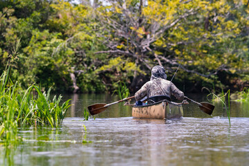 Lone fisherman paddling canoe