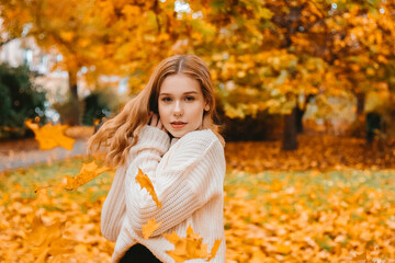 Photo portrait of a girl in a white sweater, beautiful brunette . Pretty woman in the park in autumn  Autumn fashion and style.