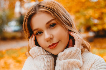 Beautiful brunette portrait in the autumn park, the girl looks at the camera and smiles easily.