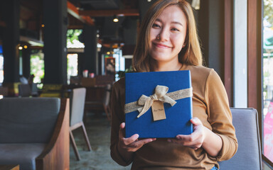 Portrait image of a young woman receiving and holding a present box