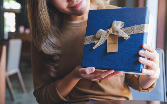 Closeup image of a young woman holding and receiving a present box