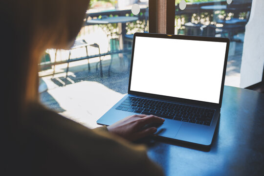 Mockup image of a woman working and touching on laptop computer with blank white desktop screen