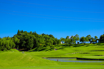 青空のゴルフ場・島になった浮きグリーンへの池越えコースの眺め（千葉県木更津市）