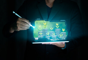 Return on investment concept. Businessman holding tablet with Plant on coin stack growing over green bokeh background,Business Finance, Earning, benefits, Capital,Save Money, fund,bond,Market growth