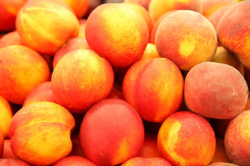 Lots of delicious looking very fresh peaches on sale at an outside market on a sunny Saturday.