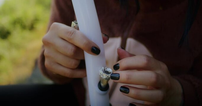 marijuana and lifestyle. a woman smokes cannabis through a bong, enjoys the effect of narcotics. medical effects of marijuana for stress relief.