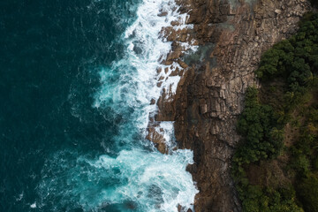 Aerial view Top down seashore big wave crashing on rock cliff
