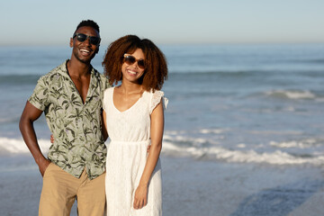 A mixed race couple posing and smiling on beach on a sunny day 