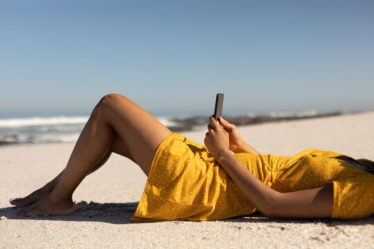 Mixed race woman using smartphone on the beach