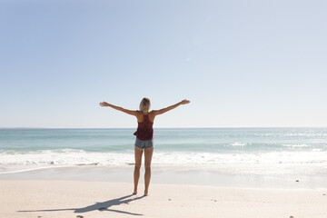 Young caucasian woman raising arms on the beach
