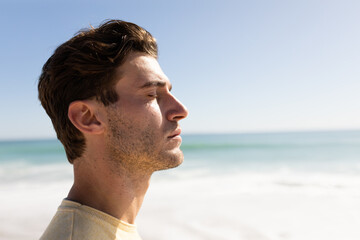 Young caucasian man closing eyes on the beach