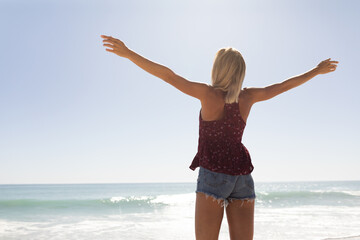 Fototapeta na wymiar Young caucasian woman raising arms on the beach