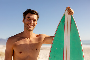 Caucasian man holding surf board on beach