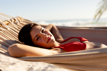 Young caucasian woman laying on hammock on beach