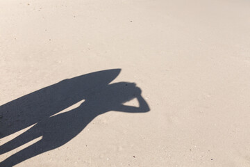 shadow of a mixed race woman holding a surfboard on the beach