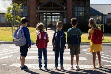 Obraz premium Schoolchildren waiting at a pedestrian crossing to cross the road