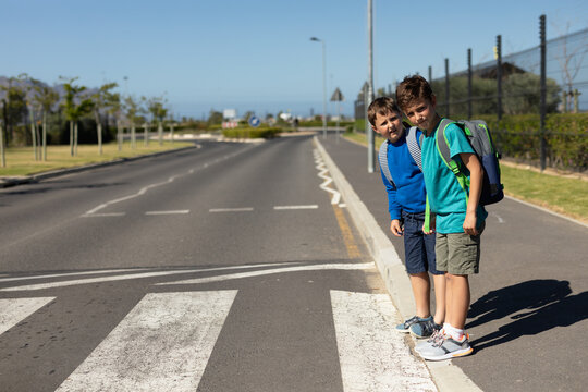 Two schoolboys looking for traffic while waiting to cross the road
