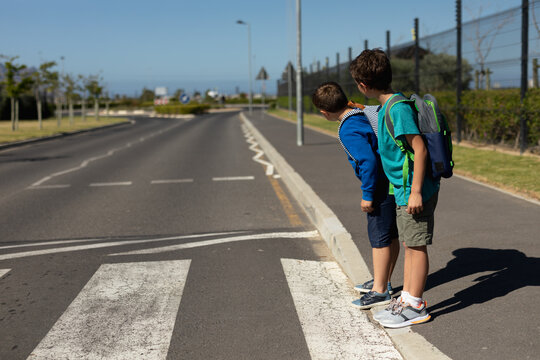 Two schoolboys looking for traffic while waiting to cross the road