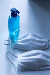Fototapeta premium Close up of a sanitizer and two white face masks for protection against coronavirus covid 19 epidemi