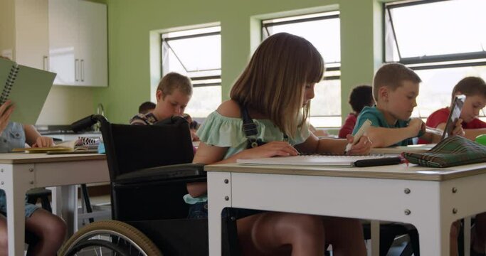 Physically challenged girl drawing in her notebook in the class