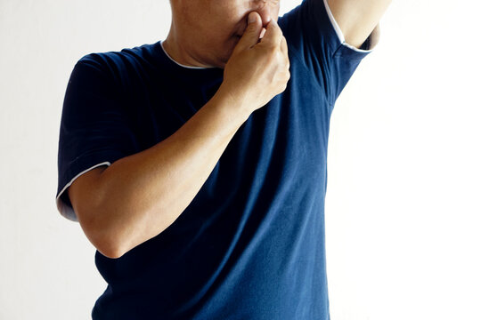 Closeup man covers his nose for his bad odor armpit, isolated on white background. Concept : health problem. Unpleasant body odor , smell nasty reaction.  Negative emotion.      