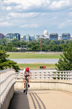 Biker On Bridge Bike Path With View Of The United States Capitol Building And Washington, DC Skyline In The Distance - Arlington, Virginia, USA (Washington, DC Metropolitan Area)