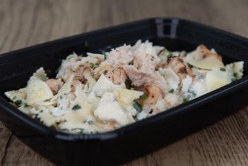 Take out order of chicken with bow tie pasta is conveniently packed in a microwavable container