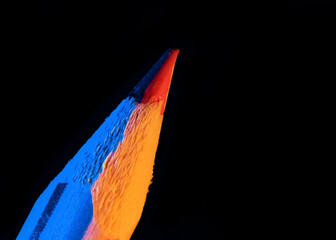 Multi color lead pencil on black background. Illuminated with blue and yellow color light