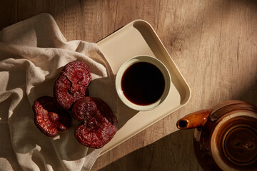 
On a tray on a wooden background, Ganoderma lucidum is displayed with a cup of tea next to.