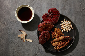 Herbal tea and a tray containing Reishi mushrooms, red ginseng, lotus seeds, and cordyceps on a...