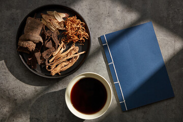 Table piled with priceless dried herbs, a cup of tea, and a book