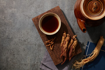 Tonic tea made with fresh ginseng and dried red ginseng is placed on a wooden podium beneath the cement floor.