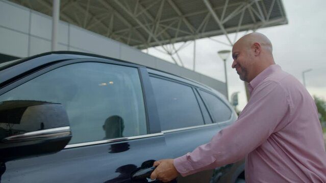 Man Waving Goodbye And Thank You To Family As He Gets Into A Rental Car.