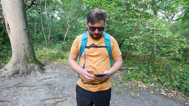 Person walking towards camera and checking digital compass on smartphone, front view slow motion