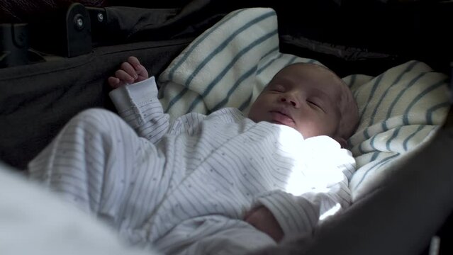 Calm asian newborn sleeping in infant car bed