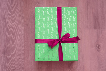 top view of green color gift box with red ribbon bow on light red background. Concept: holiday, celebration, birthday, New Year, Christmas, Valentines Day, Mothers Day, Thanksgiving